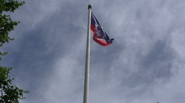 Juneteenth flag flies in a partly cloudy sky.