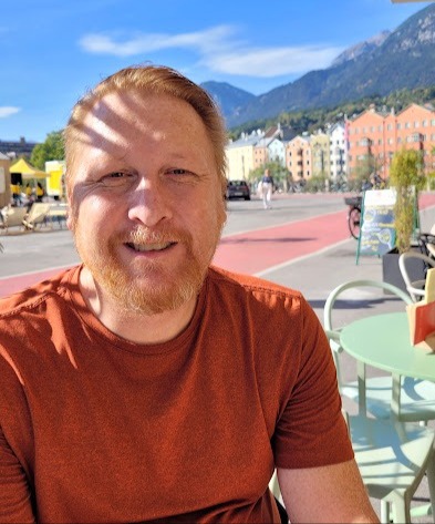 Young man sitting on patio in a European town.