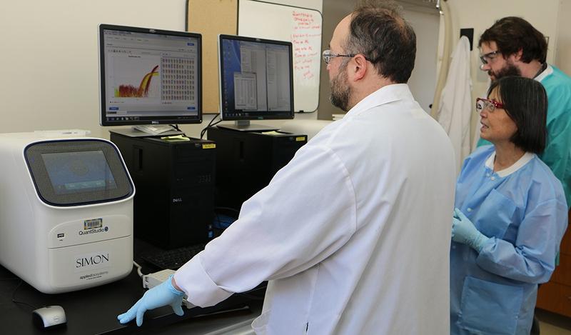 Three scientists look at graphs on a computer