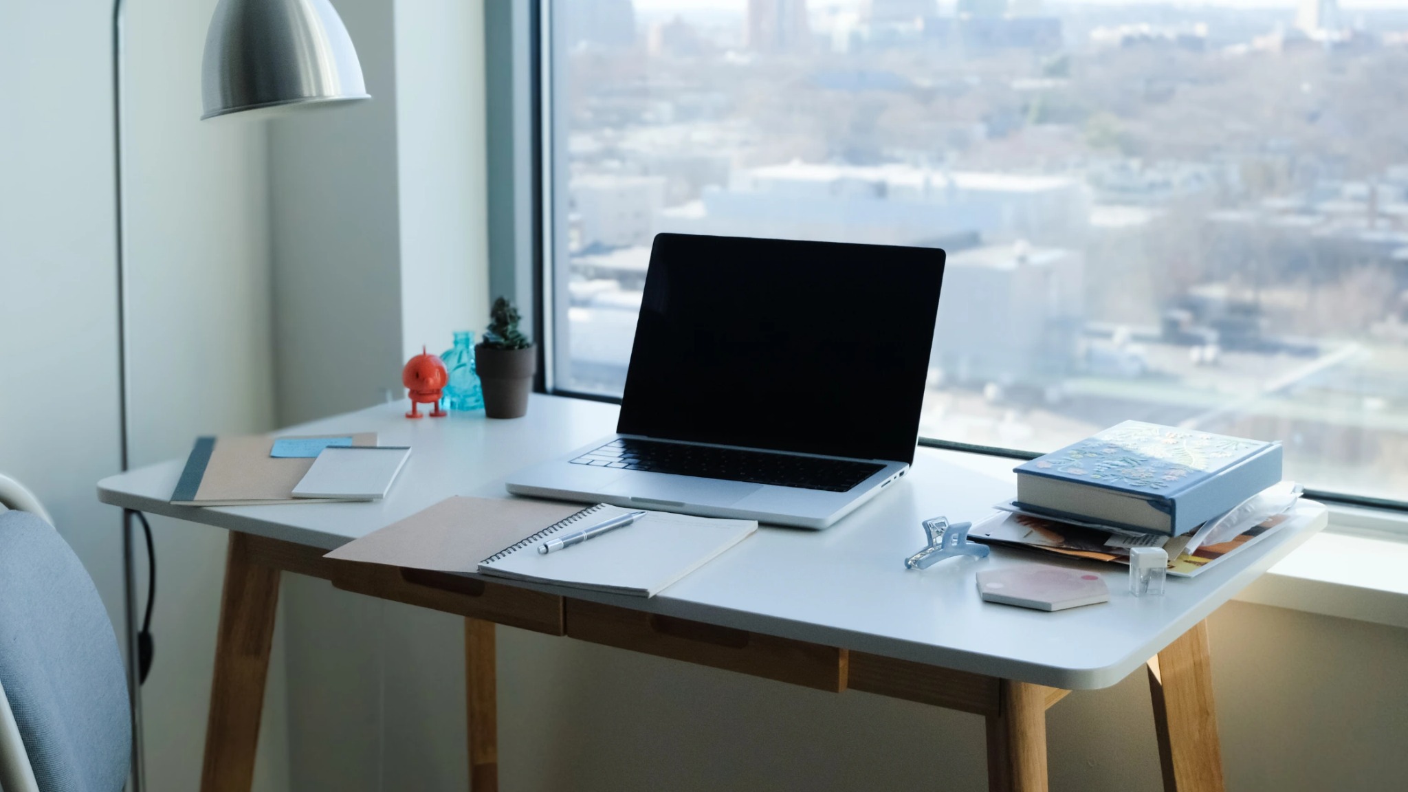 : A clean, organized minimalist home office setup featuring a laptop and notebook, representing the efficiency of virtual assistant services.