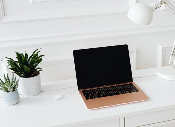Clean white office desk featuring a laptop and a small globe, representing the remote workflow discussed in Do You Really Need a Virtual Assistant? (When to Hire One).