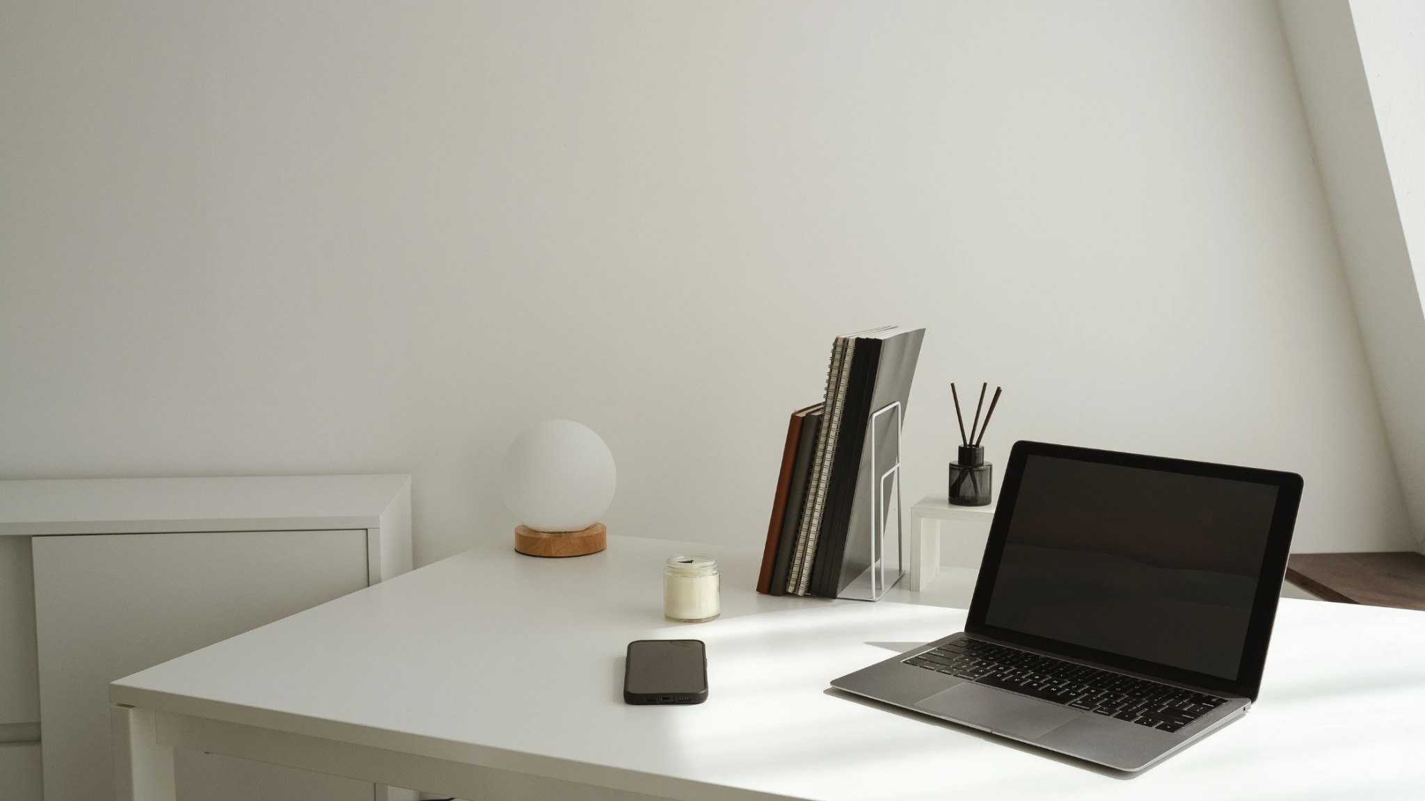 : A clean, organized minimalist home office setup featuring a laptop and notebook, representing the efficiency of virtual assistant services.