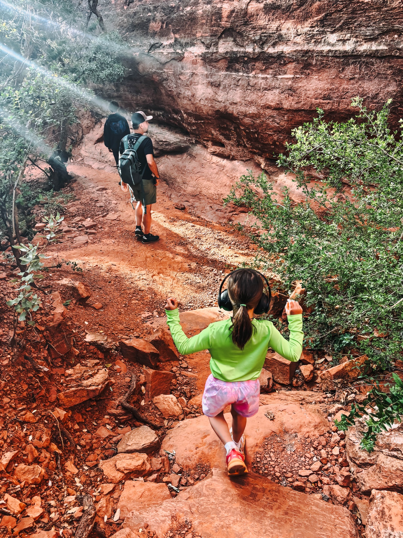 Family hiking an Arizona trail with a child wearing noise-canceling headphones
