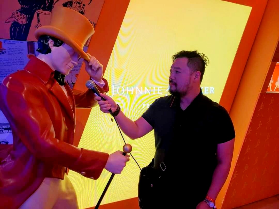 Adrian Ma pretends to interview a statue of Johnnie Walker