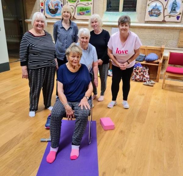 A group of women participating in a chair yoga session at a community center with Daisy Chain Yoga.