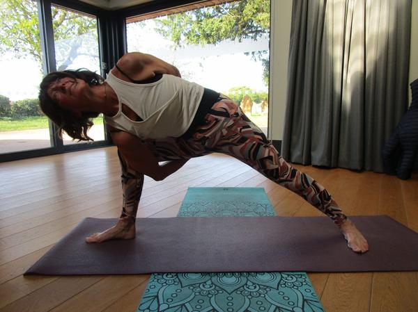 Rachel Metcalfe of Daisy Chain Yoga practicing a bound side angle pose (Baddha Utthita Parsvakonasana) in a bright, modern studio.