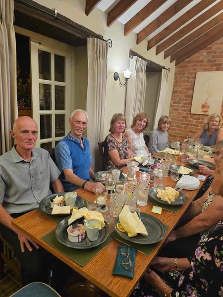 A group of Daisy Chain Yoga students enjoying a social dinner together at a rustic restaurant with exposed brick and wooden beams.