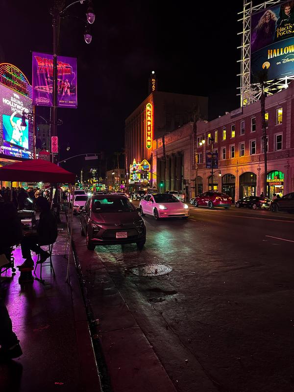 Hollywood Boulevard at night with neon signs, traffic, and the El Capitan Theatre marquee