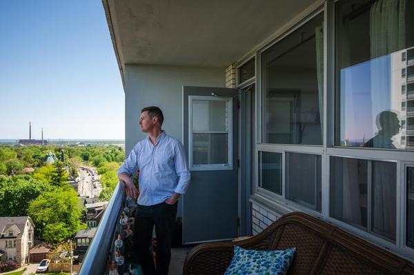 Ian Eatock stands on the balcony of his apartment on Broadview Avenue in Toronto, in May.