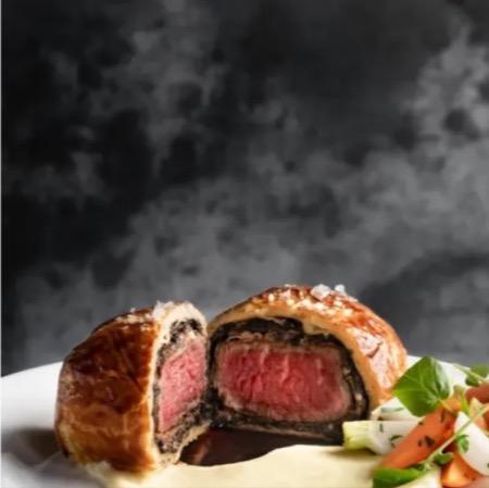A plate of beef wellington and vegetables