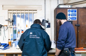 Two men working together at a bench during a practical training session in a prison workshop.