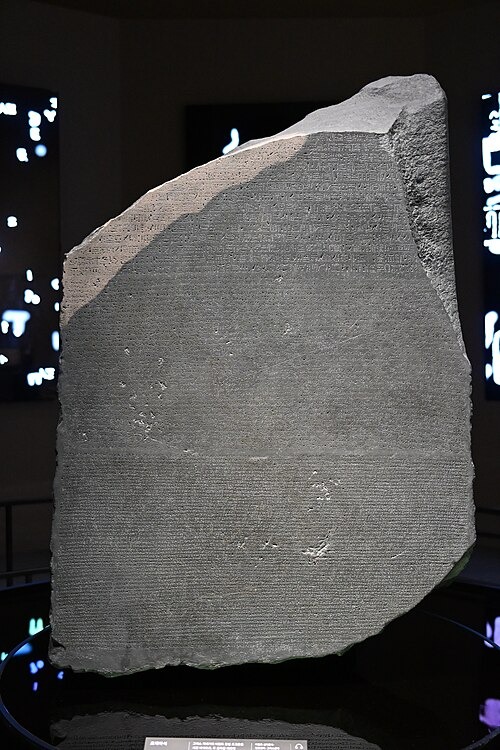 Replica of the Rosetta Stone on display, showing the inscribed text carved across the dark stone surface.