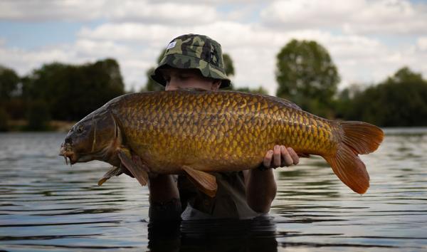 Man holding fish in water. Photographed by Lowes Creative Media