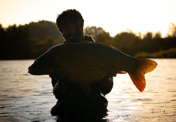 Jared, Owner of Solid Angling Solutions. holding fish in water. Photographed by Lowes Creative Media