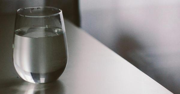 A glass of water on a gray table A glass of water on a gray table
