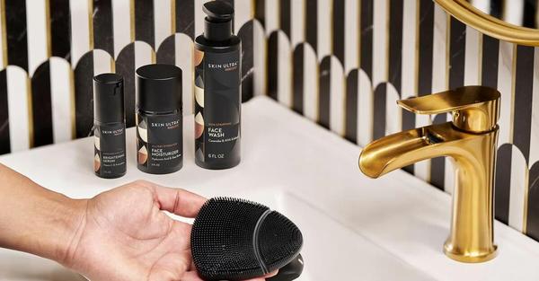 A hand holding an exfoliating sponge over a sink