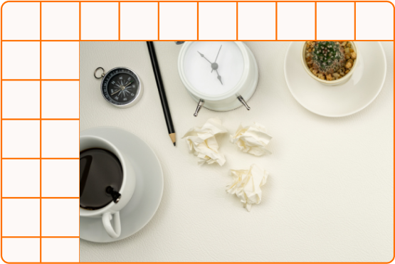 A coffe cup, alarm clock, plant, pencil, and paper laid out on a white desktop space A coffe cup, alarm clock, plant, pencil, and paper laid out on a white desktop space